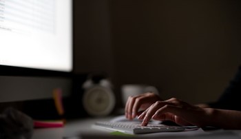 Person sits at a desk answering emails in a dark room
