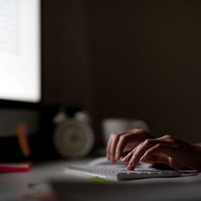 Person sits at a desk answering emails in a dark room