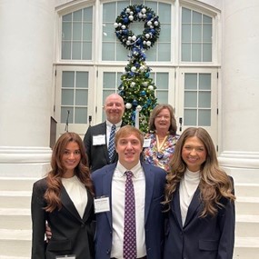students and faculty posing for a photo in front of a large glass door