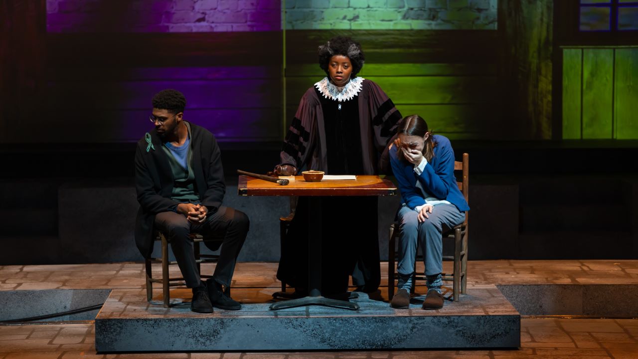 Judge presiding over two citizens, a man looking away and a woman crying, in the show Wellesley Girl