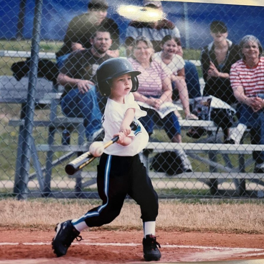 A young Noah Griffith hits a baseball as his family watches from the stands