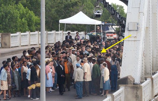 An yellow arrow points to Lowery McNeal in a crowd of extras filming Selma on the Edmund Pettus Bridge