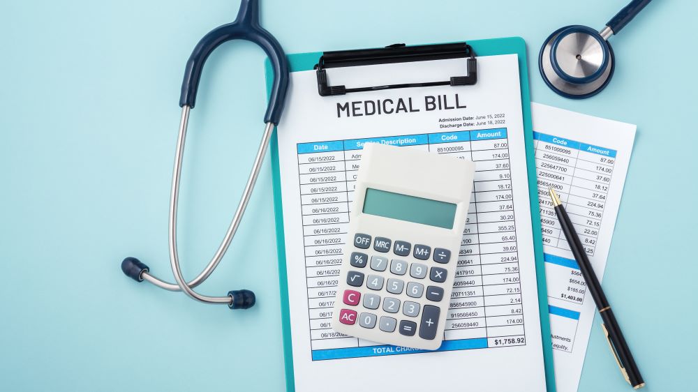 A stethoscope and calculator sitting atop a stack of medical bills